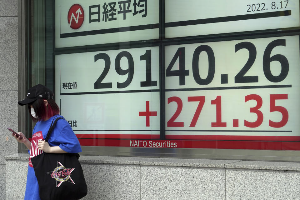 A person wearing a protective mask stands in front of an electronic stock board showing Japan's Nikkei 225 index at a securities firm Wednesday, Aug. 17, 2022, in Tokyo. Asian shares were mostly higher Wednesday as regional markets looked to strong economic signs out of the U.S. and China as drivers of growth. (AP Photo/Eugene Hoshiko)