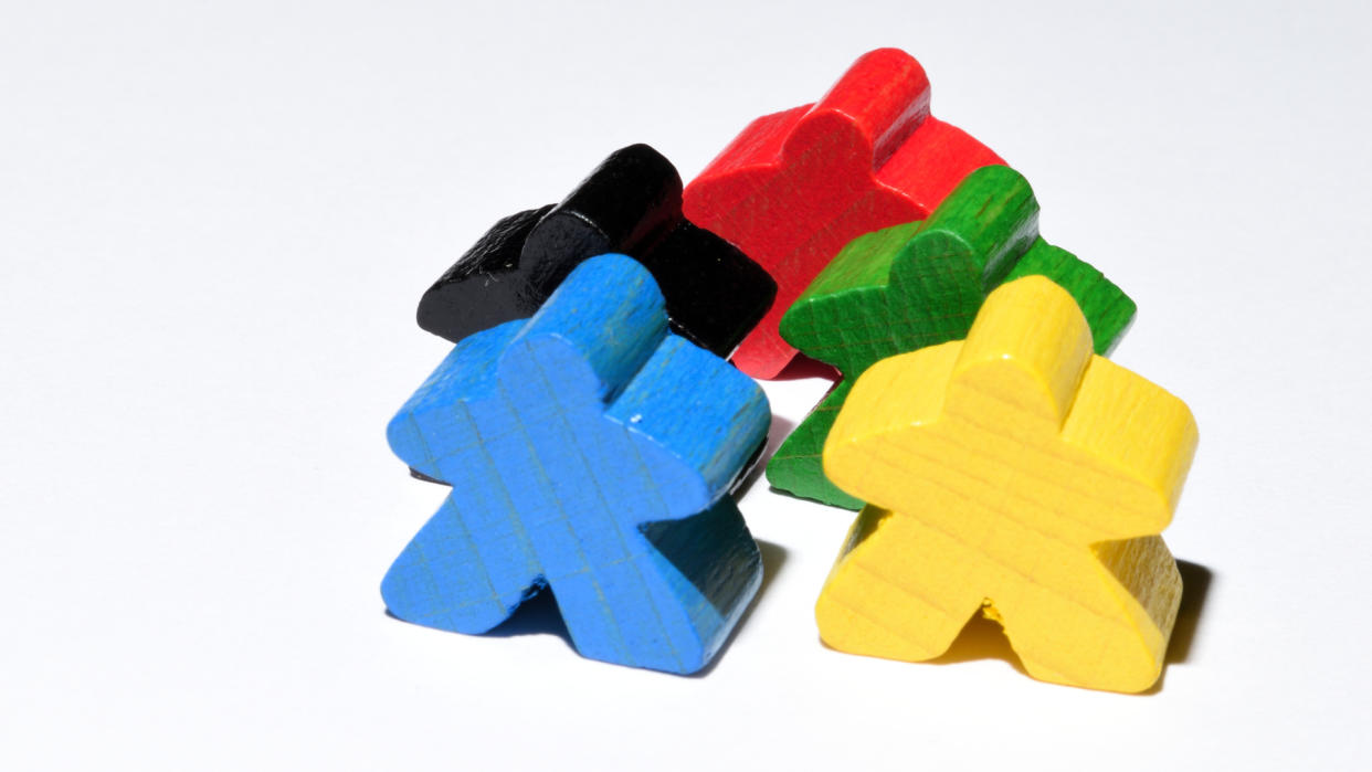  Four wooden meeples in various colors. 