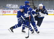 Winnipeg Jets left wing Nikolaj Ehlers (27) gets hit and looses his stick by Toronto Maple Leafs defenseman Jake Muzzin (8) as Maple Leafs left wing Zach Hyman (11) looks for the puck during second period NHL hockey action in Toronto on Monday, Jan. 18, 2021. (Nathan Denette/The Canadian Press via AP)