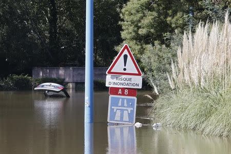 A traffic warning sign reads, "Danger of Flooding" near an abandoned car that is submerged in deep water near the autoroute after flooding caused by torrential rain in Mandelieu, France, October 4, 2015. REUTERS/Eric Gaillard