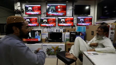 Shopkeepers talk as television screens display the coverage of the World Court review of the death penalty given to former Indian navy commander Kulbhushan Sudhir Jadhav, at a shop in Karachi