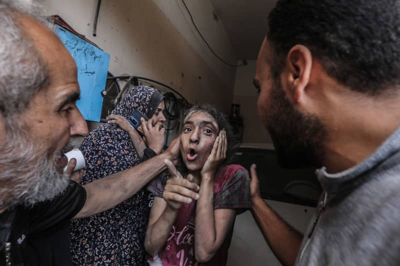 A Palestinian young girl holds hear ear as she speaks after the Israeli bombing of a populated residential building in Nuseirat. Omar Naaman/dpa