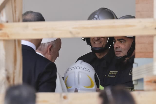 Pope Francis is offered a safety helmet during his visit 