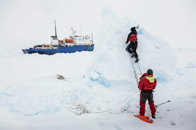 In this Tuesday, Dec. 31, 2013 image provided by Australasian Antarctic Expedition/Footloose Fotography, Ben Maddison and Ben Fisk from the Russian ship MV Akademik Shokalskiy work to place a wind indicator atop an ice feature near the trapped ship 1,500 nautical miles south of Hobart, Australia. Passengers on board a research ship that has been trapped in Antarctic ice for a week are expected to be rescued by helicopter, after three icebreakers failed to reach the paralyzed vessel, officials said Tuesday. (AP Photo/Australasian Antarctic Expedition/Footloose Fotography, Andrew Peacock) EDITORIAL USE ONLY