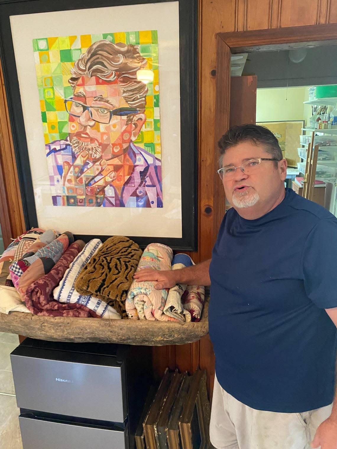 Will Hinton next to a self-portrait in his Louisburg studio, where he will continue to work after his retirement from Louisburg College.