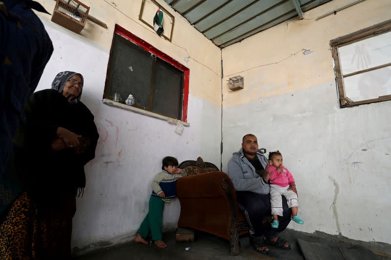 Palestinian man Eyad Al-Zahar carries his niece as he sits in his home in Gaza City