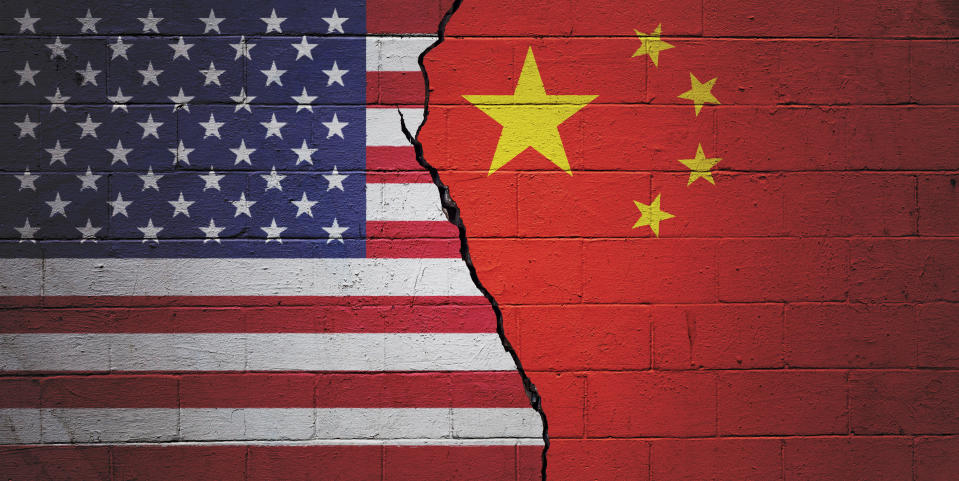 Cracked brick wall painted with an American flag on the left and a Chinese flag on the right.