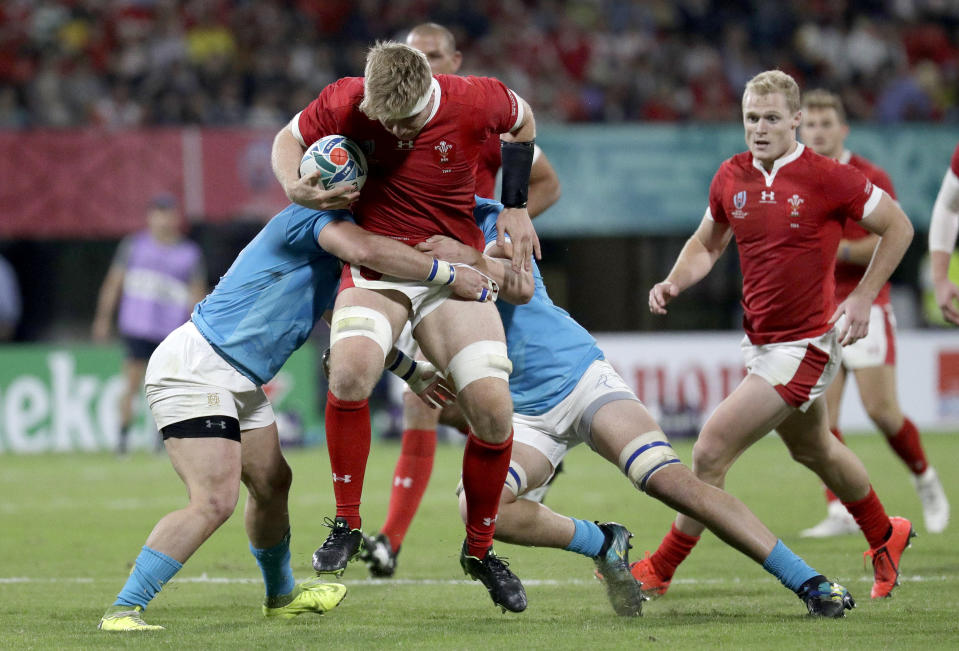 Wales' Aaron Wainwright is tackled by defenders during the Rugby World Cup Pool D game at Kumamoto Stadium between Wales and Uruguay in Kumamoto, Japan, Sunday, Oct. 13, 2019. (AP Photo/Aaron Favila)