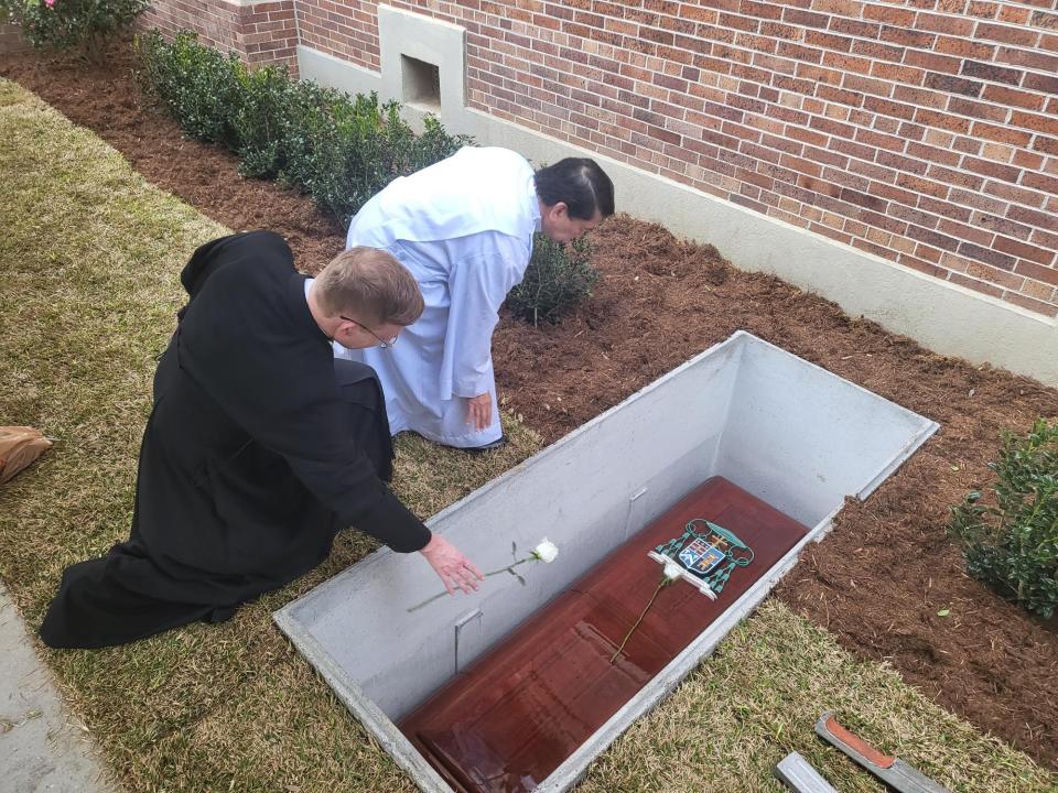 Rev. Patrick Riviere and Rev. Dela Cruz drop white roses on the casket of the late Bishop Mario Dorsonville, February 1, at the St. Joseph Co-Cathedral in Thibodaux.