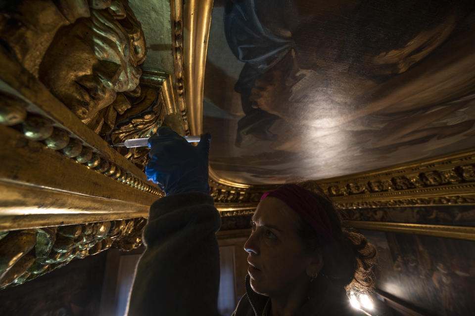 Restorer Romana Albini works, Wednesday, Dec. 6, 2022, in the Consiglio dei Dieci Hall inside Palazzo Ducale in Venice, northern Italy, on the gilded carved wooden ceiling surrounding Jacopo D'Andrea's 1863 copy of Paolo Veronese's oil on canvas 'Jupiter Hurling Thunderbolts at the Vices', confiscated by the art commissars of Napoleon Bonaparte and removed to Paris in 1797. (AP Photo/Domenico Stinellis)