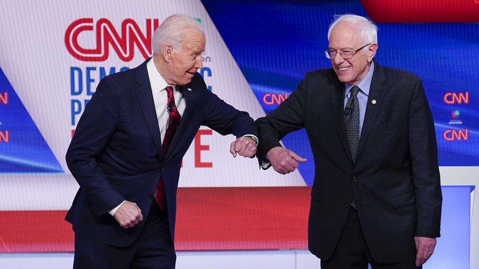 Former Vice President Joe Biden, left, and Sen. Bernie Sanders, I-Vt., right, greet one another before they participate in a Democratic presidential primary debate at CNN Studios in Washington, Sunday, March 15, 2020. (AP Photo/Evan Vucci)