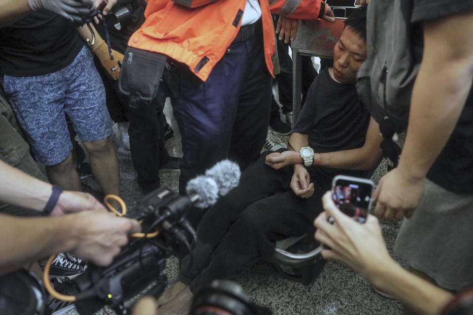 Cameramen and photographers film a detained man, who protesters claimed was a police officer from mainland China, on a luggage trolley during a demonstration at the Airport in Hong Kong, Tuesday, Aug. 13, 2019. (Photo: Vincent Yu/AP)