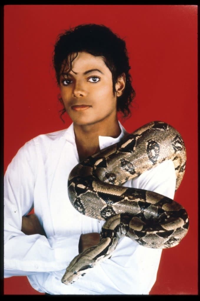 Michael Jackson poses with a snake wrapped around his shoulders, wearing a white shirt