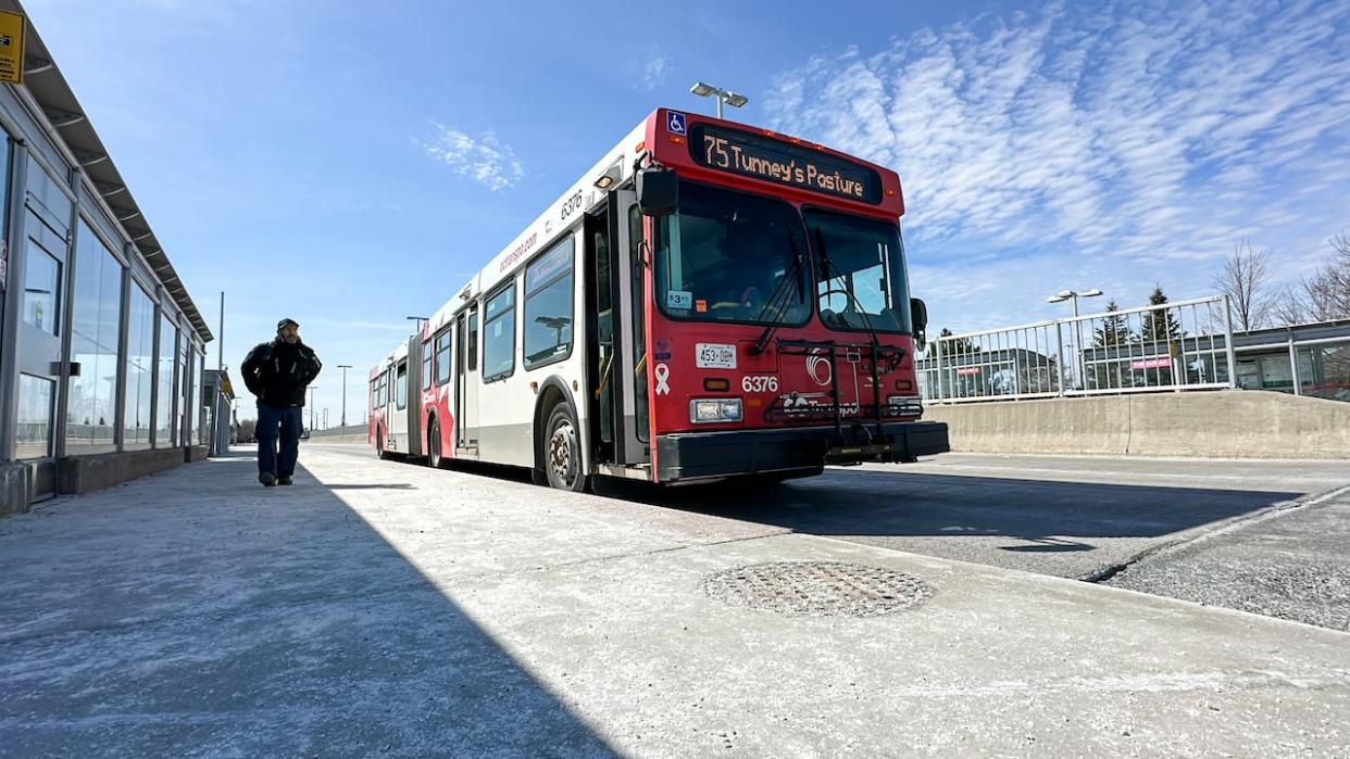 An OC Transpo bus pulls up to a stop on Monday. The transit system will see a major overhaul when the Trillium Line returns, which is expected in spring or summer. (Stu Mills/CBC - image credit)