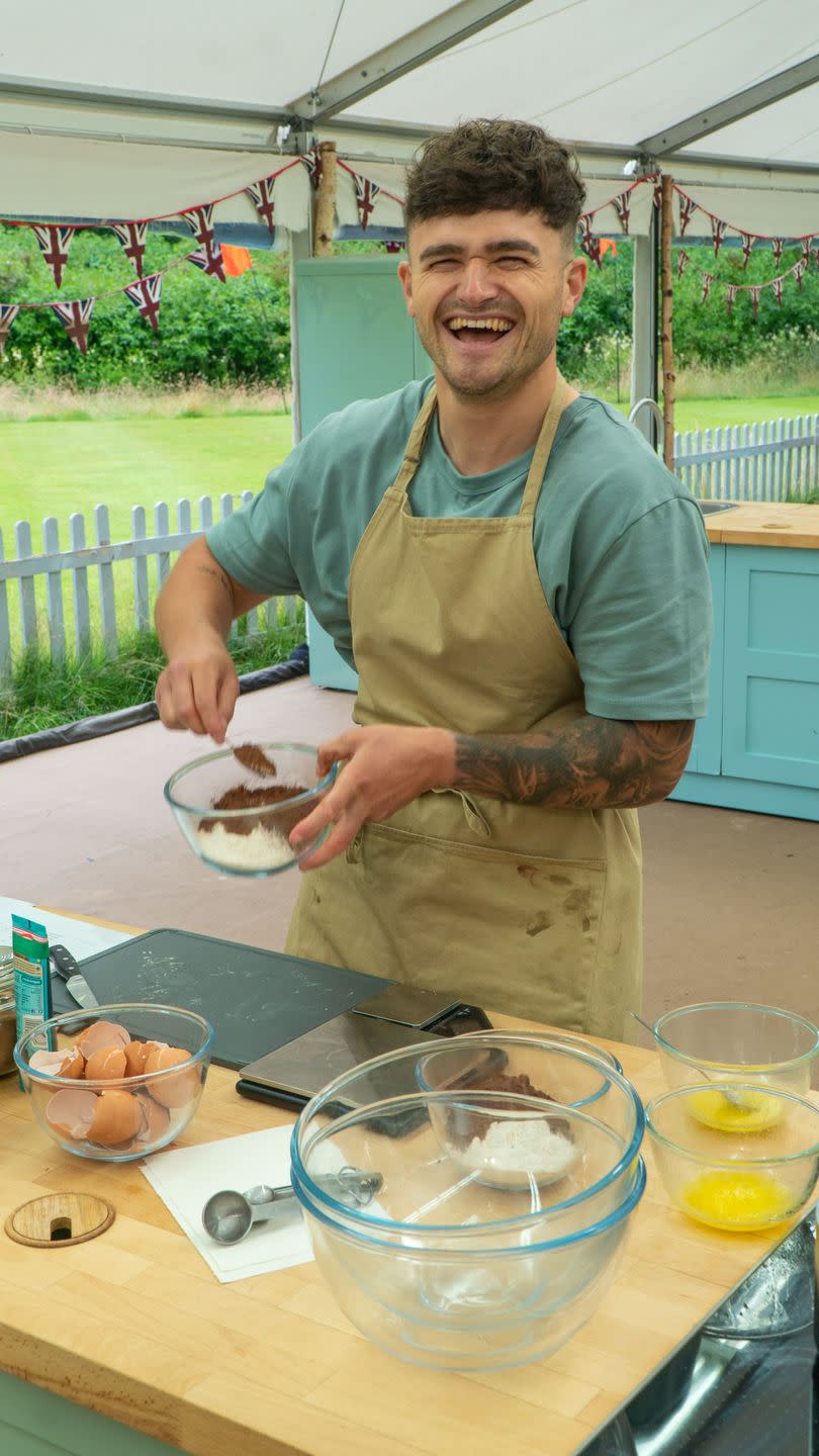 matty, a man smiles at the camera while stirring ingredients on the great british bake off 2023