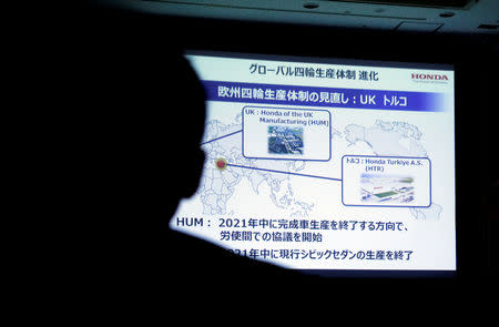 A journalist looks at a projection about Honda's British factory while Honda Motor Chief Executive Takahiro Hachigo (not in the picture) speaks at a news conference in Tokyo, Japan, February 19, 2019. REUTERS/Kim Kyung-hoon