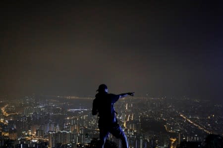 Anti-government protester reacts as he moves part of the "Statue of Lady Liberty Hong Kong" on the iconic Lion Rock in Hong Kong