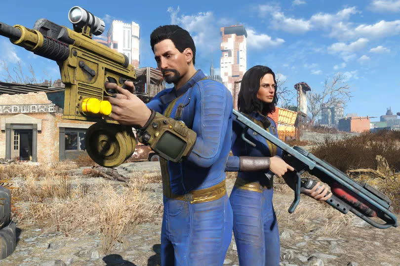 A screenshot from Fallout 4 showing a man and a woman in blue and yellow jumpsuits, holding weapons in front of a barren landscape