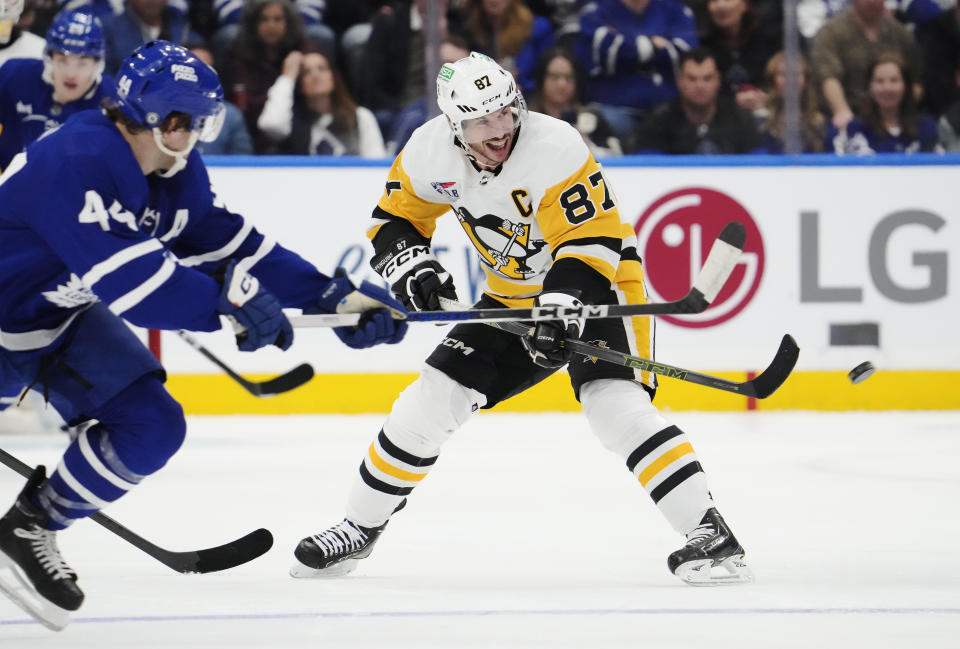 Pittsburgh Penguins' Sidney Crosby (87) passes as Toronto Maple Leafs' Morgan Rielly (44) defends during the third period of an NHL hockey game in Toronto on Monday, April 8, 2024. (Frank Gunn/The Canadian Press via AP)