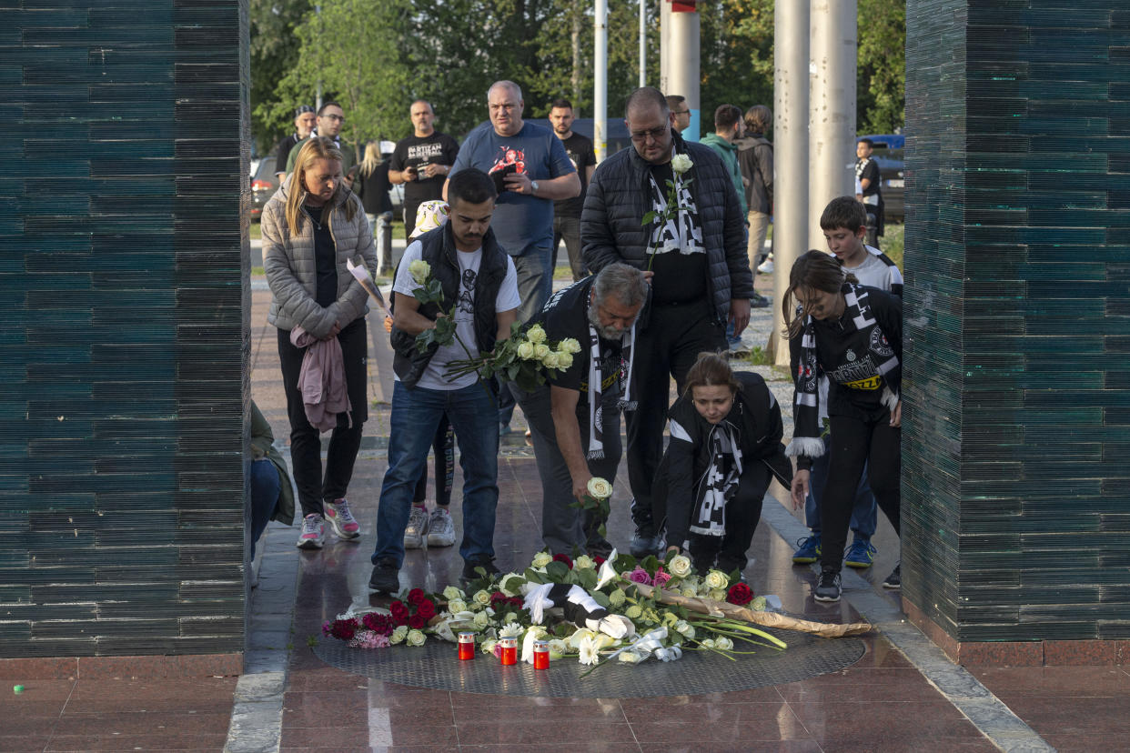 Partizan Belgrade fans lay flowers at a makeshift shrine to commemorate victims prior to a Euroleague basketball match in Belgrade, Serbia, Thursday, May 4, 2023. A 13-year-old opened fire Wednesday at his school in Serbia's capital, killing eight fellow students and a guard before calling the police and being arrested. Six children and a teacher were also hospitalized. (AP Photo/Marko Drobnjakovic)