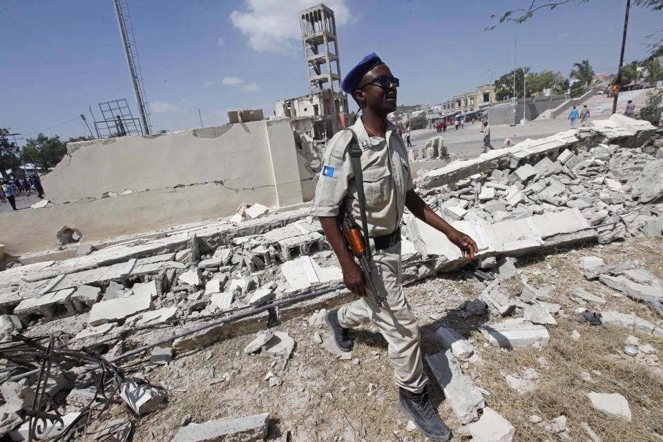 A police officer walks through the debris of a destroyed building following a large blast in Mogadishu, Somalia, Saturday, Dec. 22, 2018. Police say a suicide car bomb exploded near the presidential palace killing and injuring a number of people. (AP Photo/Farah Abdi Warsameh)