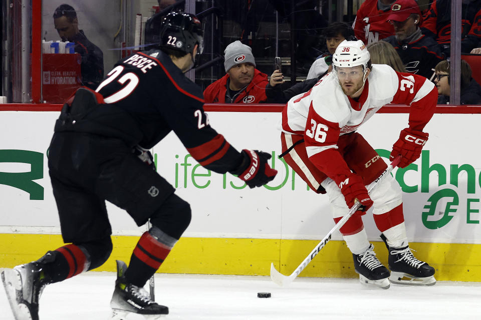 Detroit Red Wings' Christian Fischer (36) controls the puck in front of Carolina Hurricanes' Brett Pesce (22) during the first period of an NHL hockey game in Raleigh, N.C., Friday, Jan. 19, 2024. (AP Photo/Karl B DeBlaker)