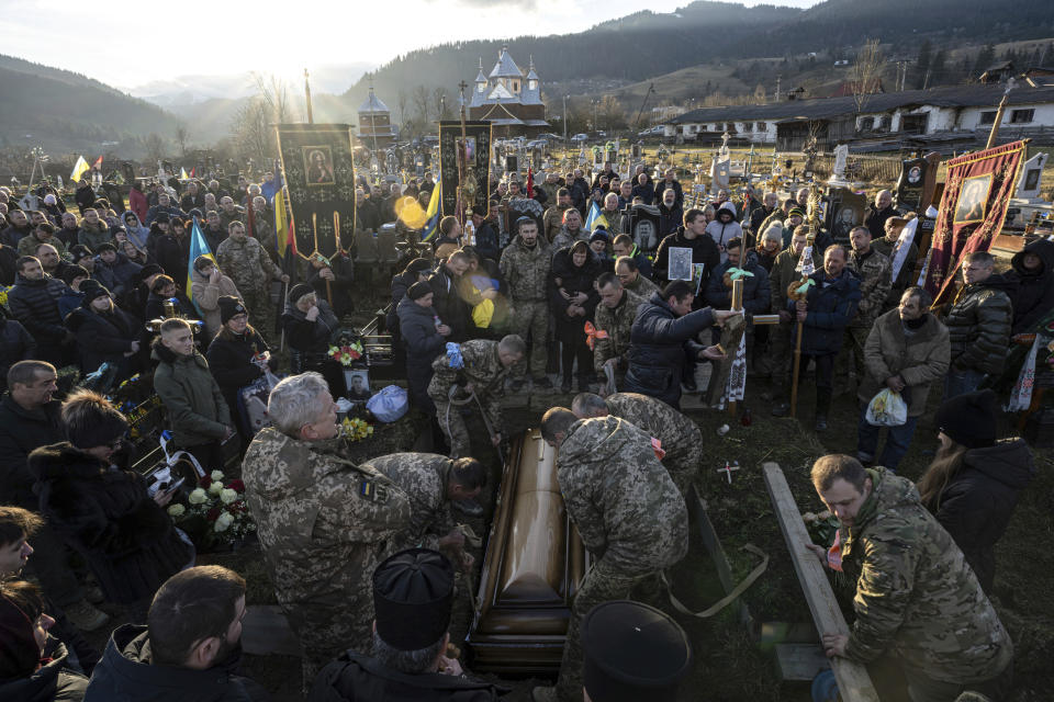 Ukrainian servicemen lower the coffin of Ukrainian army officer Vasyl Medviychuk into a grave at a cemetery in the Carpathian mountains in Krasnyk village, Ukraine, Friday, Dec. 29, 2023. (AP Photo/Evgeniy Maloletka)