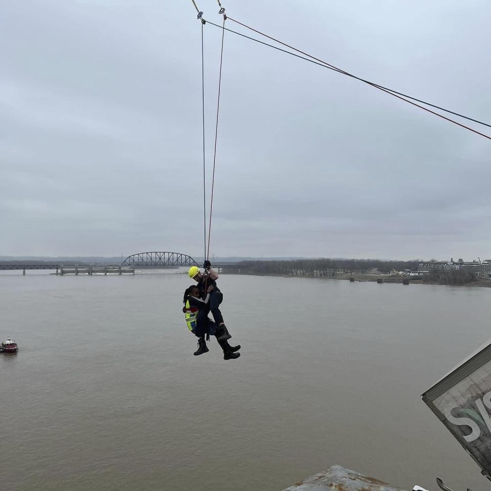 This photo provided by Louisville Division of Fire, Louisville Fire Dept. Louisville firefighter Bryce Carden rescues the driver of semitruck that is dangling off the Clark Memorial Bridge over the Ohio River on Friday, March 1, 2024 in Louisville, Ky. The driver was pulled to safety by firefighters following the three-vehicle crash on the bridge connecting Louisville, Kentucky to southern Indiana(Louisville Division of Fire via AP)