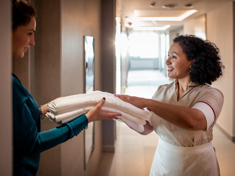 A hotel worker hands a travel clean towels.