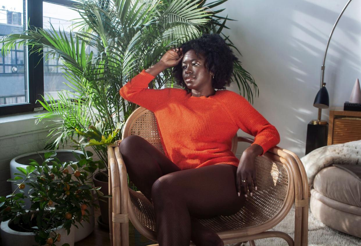 Woman wearing orange sweater and brown fishnet tights