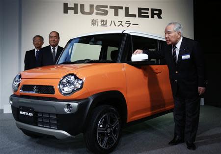 Suzuki Motor Corp Chairman and Chief Executive Officer Osamu Suzuki (R), Executive Vice President Minoru Tamura (C), and Executive Vice President Osamu Honda pose next to the new boxy minicar "Hustler" during its unveiling event in Tokyo December 24, 2013. REUTERS/Yuya Shino