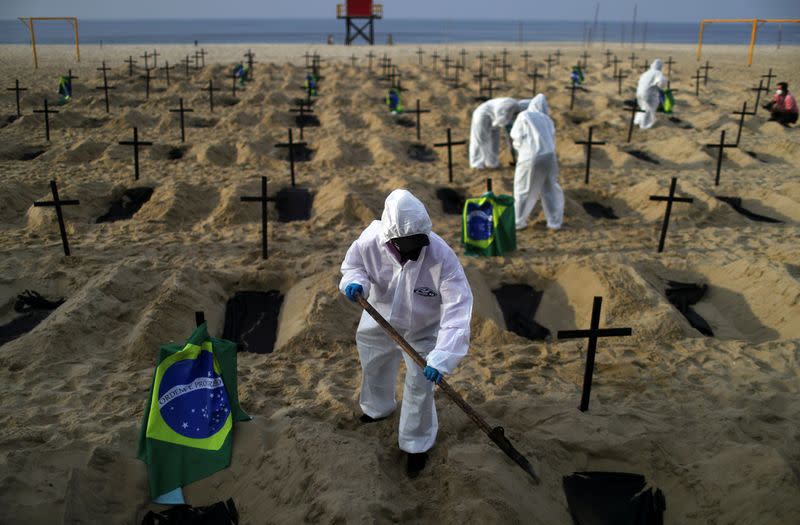 Activistas de la ONG Río de Paz con equipo de protección cavan tumbas en la playa de Copacabana para simbolizar a los muertos por la enfermedad del coronavirus (COVID-19) durante una manifestación en Río de Janeiro