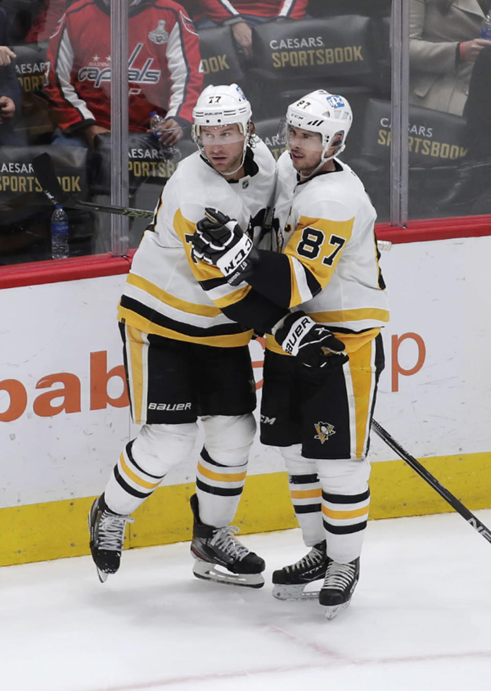 Pittsburgh Penguins' Jeff Carter (77) celebrates with teammate Sidney Crosby (87) after Carter scored an empty-net goal against the Washington Capitals during the third period of an NHL hockey game, Friday, Dec. 10, 2021, in Washington. (AP Photo/Luis M. Alvarez)