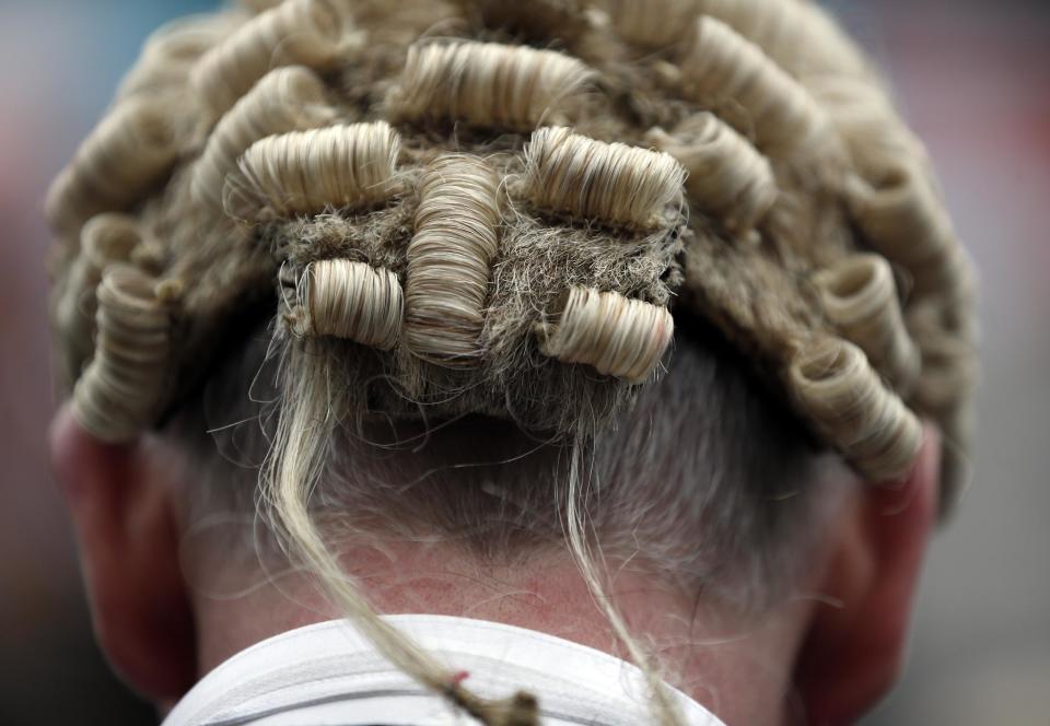 A lawyer in his full court dress of wig and gown, participates in a rally to protest against legal aid cuts, across from the Houses of Parliament in central London, Friday, March 7, 2014. The protest coincides with a nationwide demonstration of non-attendance of lawyers which will affect hundreds of cases across the country. (AP Photo/Lefteris Pitarakis)