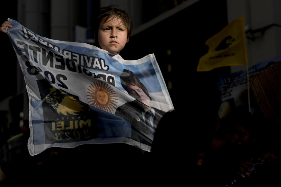 A supporter of presidential candidate Javier Milei holds a flag with his picture outside his headquarter during the presidential runoff election in Buenos Aires, Argentina, Sunday, Nov. 19, 2023. (AP Photo/Rodrigo Abd)
