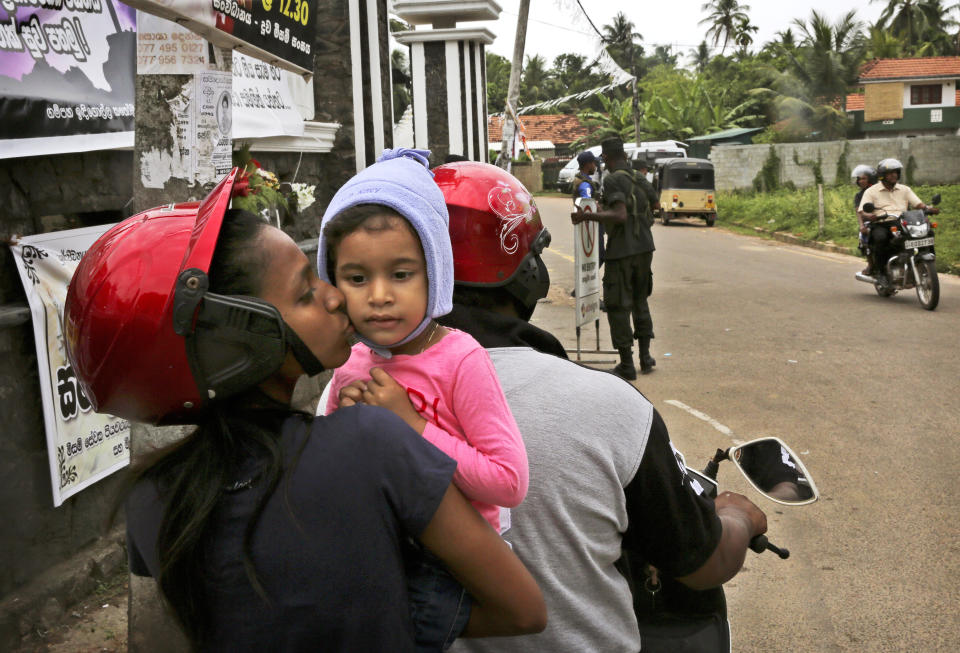 A Sri Lankan Christian mother kisses her daughter as they stop their two wheeler to have a look at the St. Sebastian's Church from outside where a suicide bomber blew himself up on Easter Sunday, in Negombo, north of Colombo, Sri Lanka, Sunday, April 28, 2019. Sri Lanka's Catholics celebrated Sunday Mass in their homes by a televised broadcast as churches across the island nation shut over fears of militant attacks, a week after the Islamic State-claimed Easter suicide bombings killed over 250 people. (AP Photo/Manish Swarup)