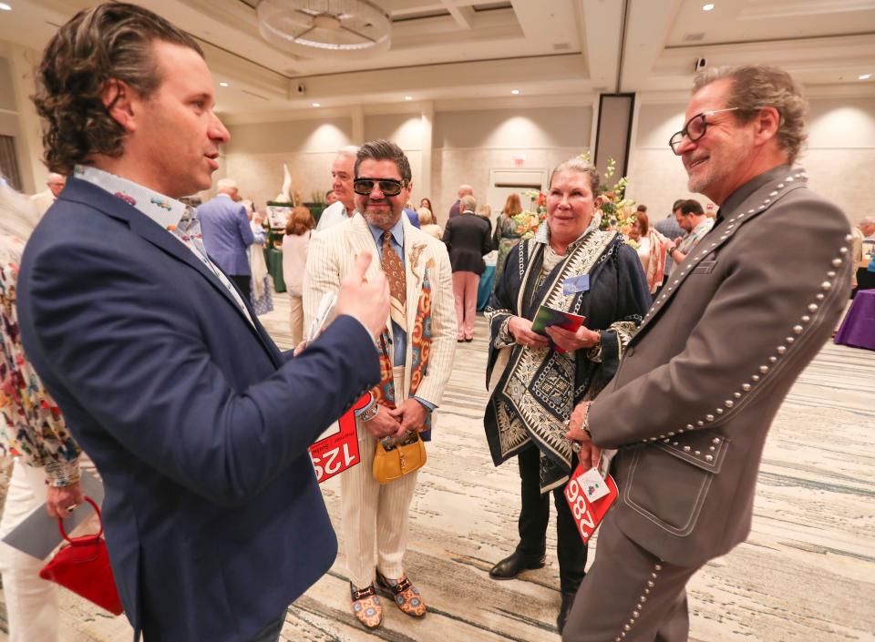 Marilyn Scripps, center right, speaks with Wilfredo Emanuel and Gary Harlan before the auction starts.