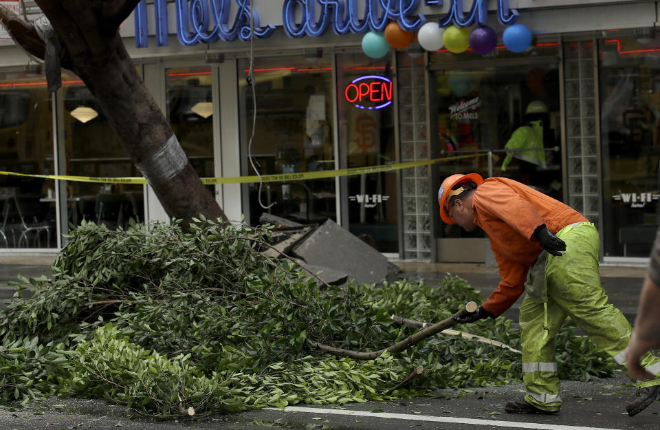 A work crew removes branches from a tree on Mission Street in San Francisco, Thursday, Jan. 17, 2019. Heavy rain, snow and wind pummeled much of California Thursday, causing at least five deaths, leaving thousands without power and forcing wildfire victims threatened by floods to flee their homes. (AP Photo/Jeff Chiu)
