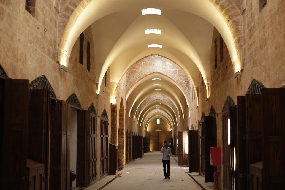 In this Saturday, July 27, 2019 photo, a Syrian man walks on the newly renovated al-Saqatiyah Market in the old city of Aleppo, Syria. Much of Aleppo's centuries-old covered market is still in ruins but slowly small parts of it have been renovated where business is slowly coming back to normal nearly three years after major battles in Syria's largest city and once commercial center came to an end. (AP Photo/Hassan Ammar)