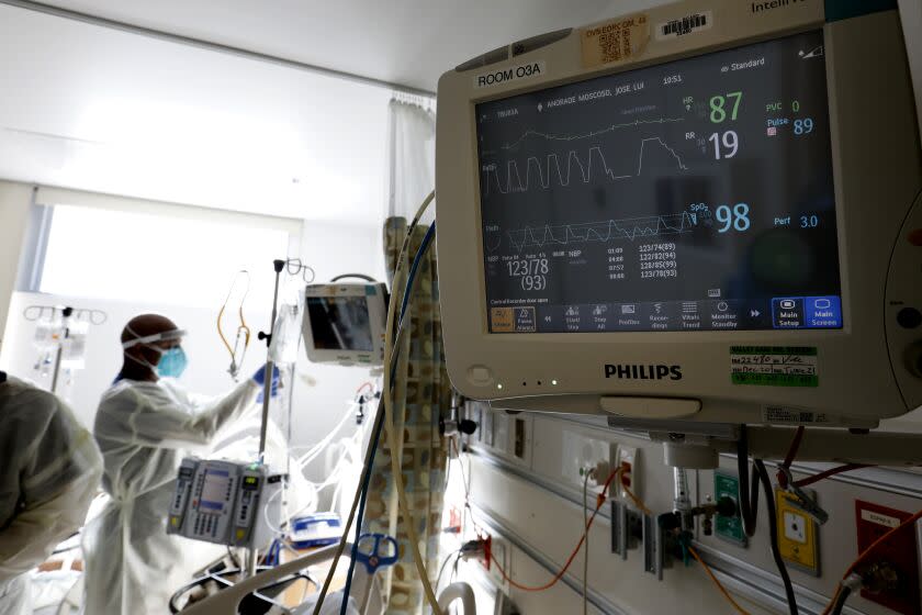 Los Angeles County, Sylmar, California-Jan. 12, 2020-Supervising RN Mesfin Meshesha, right, checks on two patients in the Covid-19 wing at Olive View-UCLA Medical Center on Jan. 11, 2020. Olive View-UCLA Medical Center is a hospital, funded by Los Angeles County, located in the Sylmar neighborhood of Los Angeles, California. It is one of the primary healthcare delivery systems in the north San Fernando Valley. (Carolyn Cole / Los Angeles Times)