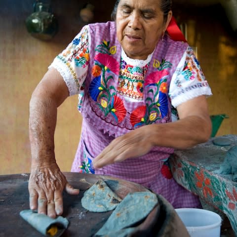 Woman cooking with blue corn tortillas and cheese at workshop in Oaxaca - Credit: Robert Landau/ Getty