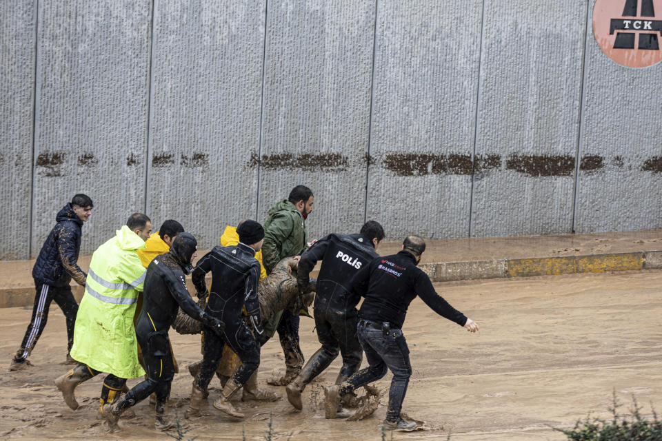 Police and rescue team members carry the body of a person during floods after heavy rains in Sanliurfa, Turkey, Wednesday, March 15, 2023. Floods caused by torrential rains hit two provinces that were devastated by last month's earthquake, killing at least 10 people and increasing the misery for thousands who were left homeless, officials and media reports said Wednesday. At least five other people were reported missing. (Ugur Yildirim/DIA via AP)