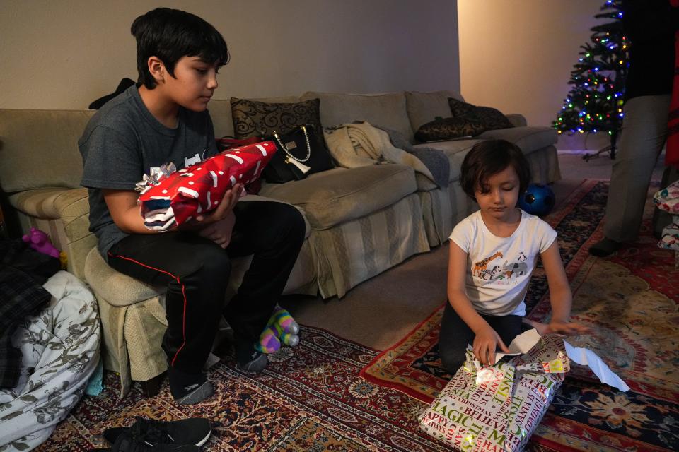 Frangiz Sherzy, right, and brother Daryosh open gifts donated by Grisham Middle School. Their mother, Shogufa Afshar, needs help with career training and English language lessons.