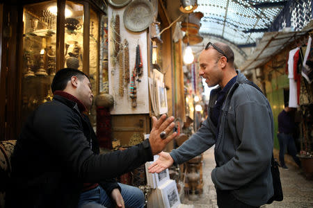 Eitan Klein, deputy director of the Israel Antiquities Authority's robbery prevention unit, greets a man near shops selling antiques at a market in Jerusalem's Old City November 25, 2018. REUTERS/Corinna Kern