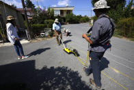 Harry M. Jol, center, a geography and anthropology professor at the University of Wisconsin Eau Claire, and his son Connor, right, operate a ground-penetrating radar as CNP staffers work together in the village of Exo Metochi, Duzova, in the Turkish occupied area at breakaway Turkish Cypriot north of ethnically divided Cyprus on Tuesday, Sept. 5, 2023. Emitting radio waves, the machine is probing for any disturbances through layers of soil beneath the asphalt to offer any clues supporting eyewitness accounts that people who vanished nearly a half century ago are buried in a makeshift mass grave, now squeezed between a two-story home and a fig orchard. (AP Photo/Petros Karadjias)