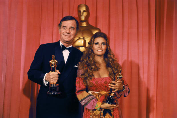 Gig Young holds Oscar he won for Best Supporting Actor of 1969 for his role in "They Shoot Horses, Don't They?" during the <a href="https://parade.com/movies/oscars-2023-academy-awards" rel="nofollow noopener" target="_blank" data-ylk="slk:Academy Awards;elm:context_link;itc:0;sec:content-canvas" class="link ">Academy Awards</a> ceremony. With him is actress Raquel Welch, who accepted the Best Supporting Actress award for absent Goldie Hawn for "Cactus Flower."<p><a href="https://www.gettyimages.com/detail/515045070" rel="nofollow noopener" target="_blank" data-ylk="slk:Bettmann/Getty Images;elm:context_link;itc:0;sec:content-canvas" class="link ">Bettmann/Getty Images</a></p>