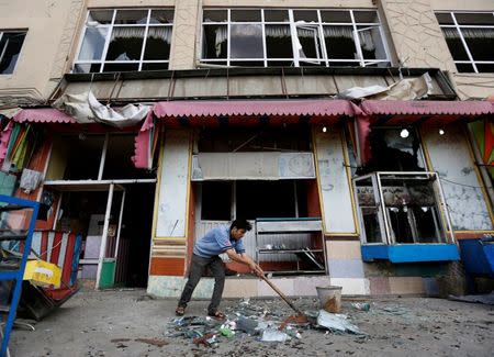 An Afghan man removes broken glass from his shop a day after a suicide attack in Kabul, Afghanistan July 24, 2016. REUTERS/Mohammad Ismail