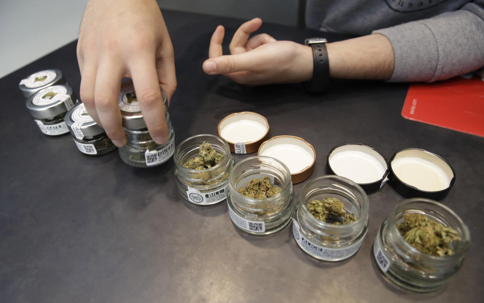 In this Thursday, June 6, 2019 a shop assistant opens jars of cannabis buds at a cannabis light store in Milan, Italy. Interior Minister Matteo Salvini has been an outspoken opponent of the marijuana light businesses that sprouted up around the country after pioneering 2016 legislation that many saw as a step toward eventual marijuana liberalization.(AP Photo/Luca Bruno)