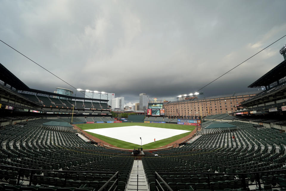 The tarp is seen over the infield at Oriole Park at Camden Yards prior to a baseball game between the Baltimore Orioles and the Washington Nationals, Friday, Aug. 14, 2020, in Baltimore. (AP Photo/Julio Cortez)