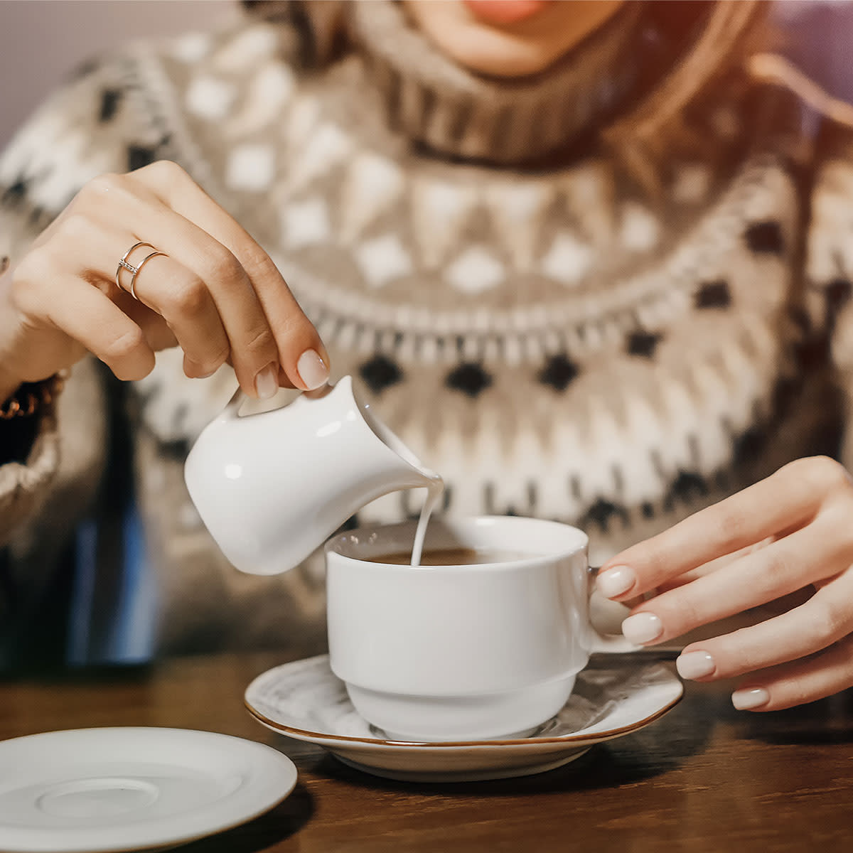 woman pouring cream into coffee